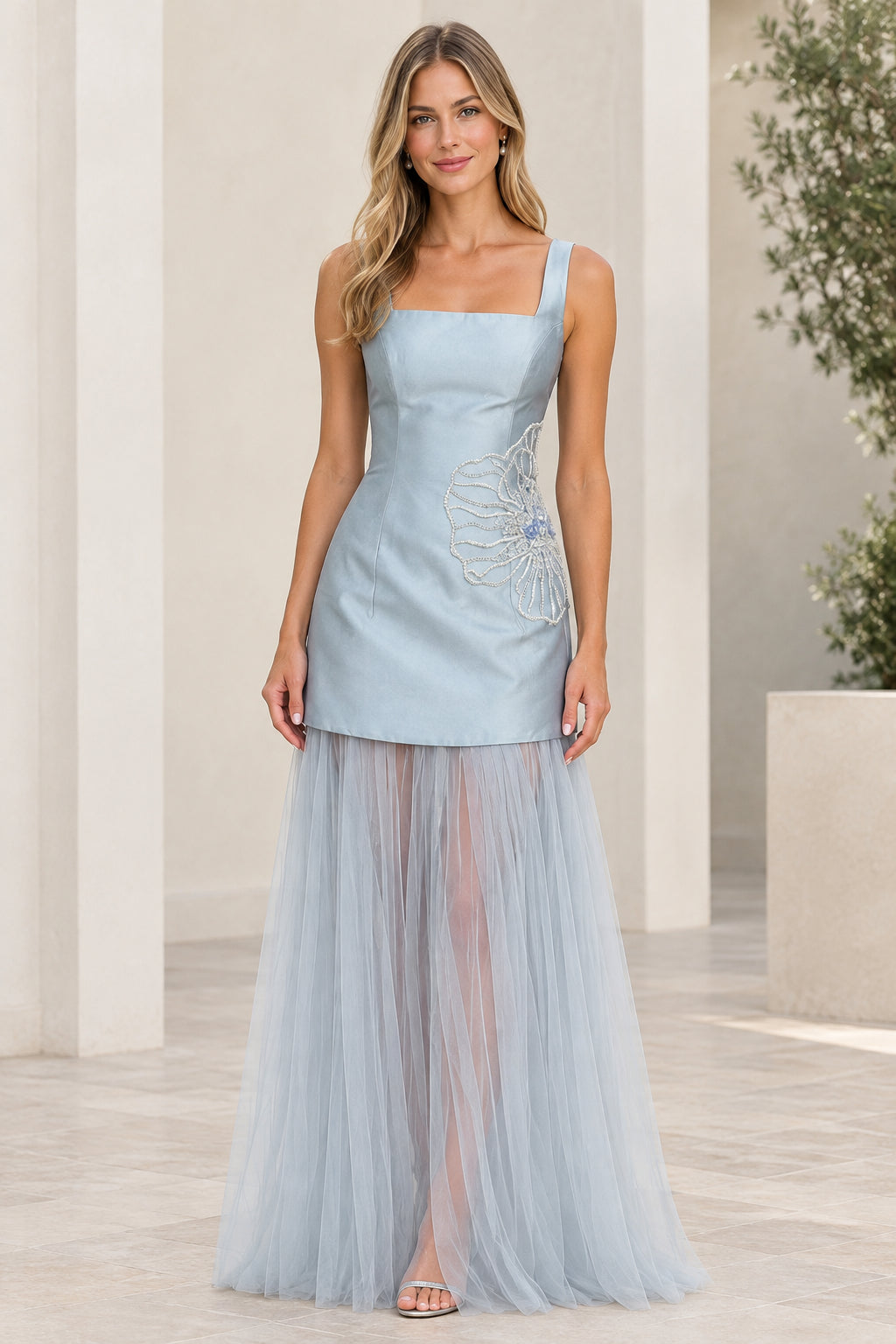 Front view of model wearing light blue square neck evening gown with sheer tulle skirt