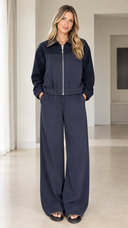 Front full view of woman wearing navy two-piece zip jacket and wide-leg pants set