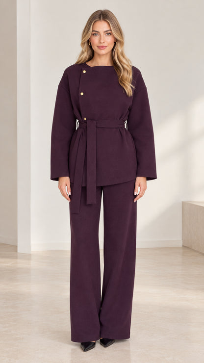 Front full-length view of woman wearing deep plum asymmetrical belted top and wide-leg pant set