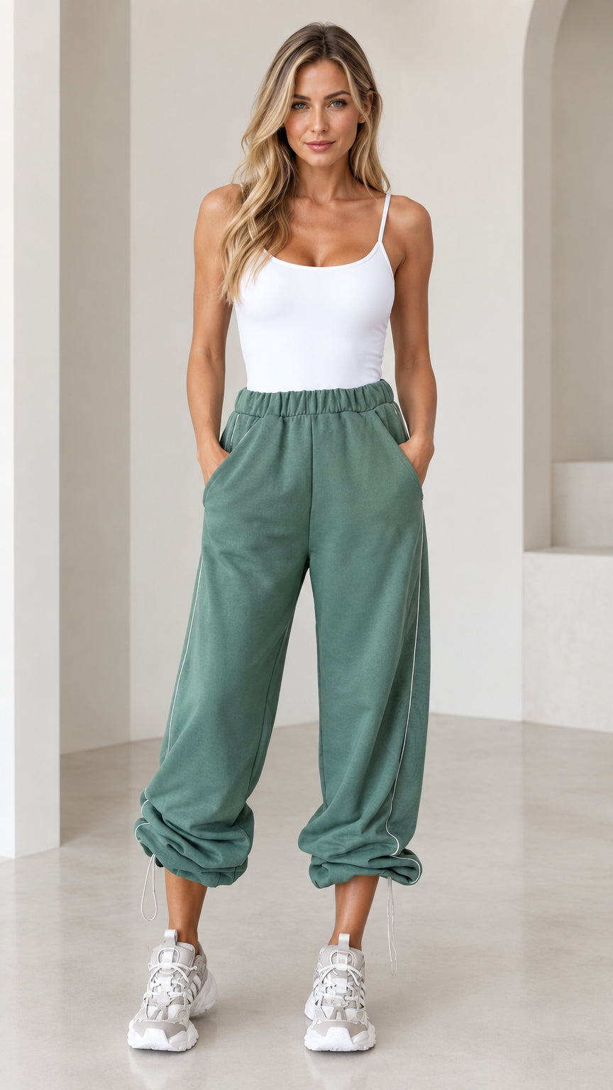 Front view of model wearing sage green relaxed cinch-bottom joggers with white tank top and sneakers