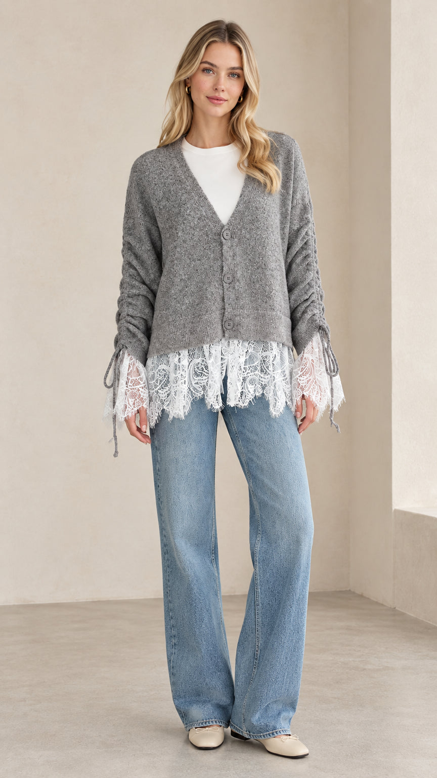 Front full view of woman wearing heather grey lace-trimmed V-neck knit cardigan with wide-leg jeans