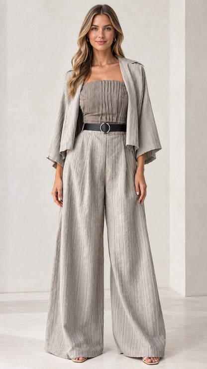 Front full-length view of woman wearing light grey pleated bandeau wide-leg jumpsuit with matching jacket and belt