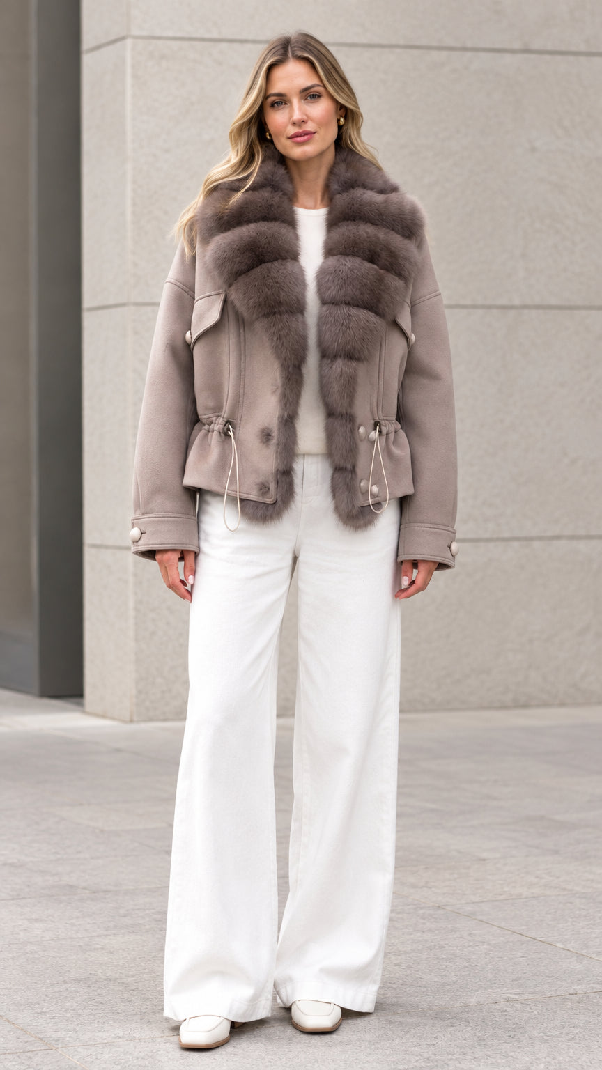 Front view of woman wearing taupe faux fur trim drawstring waist short coat with white trousers