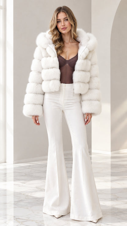 Front view of model wearing white cropped hooded faux fur jacket with white flare pants