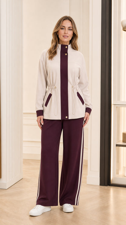 Full front view of model wearing beige high-neck tracksuit jacket with burgundy trim and matching wide-leg pants