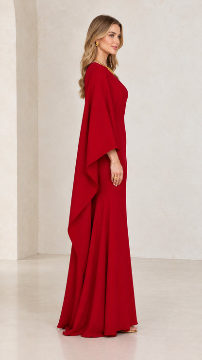Side profile of model wearing red floor-length cape sleeve formal dress