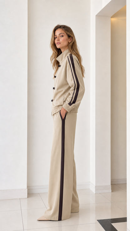 Side profile view of beige two-piece tracksuit showing contrast sleeve and leg stripes