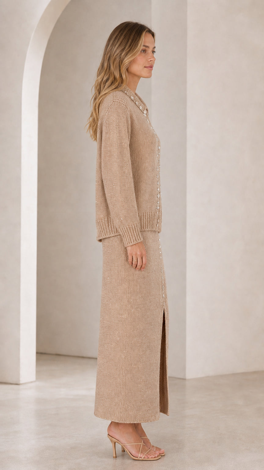 Side profile view of woman wearing beige knit two-piece cardigan and maxi skirt set