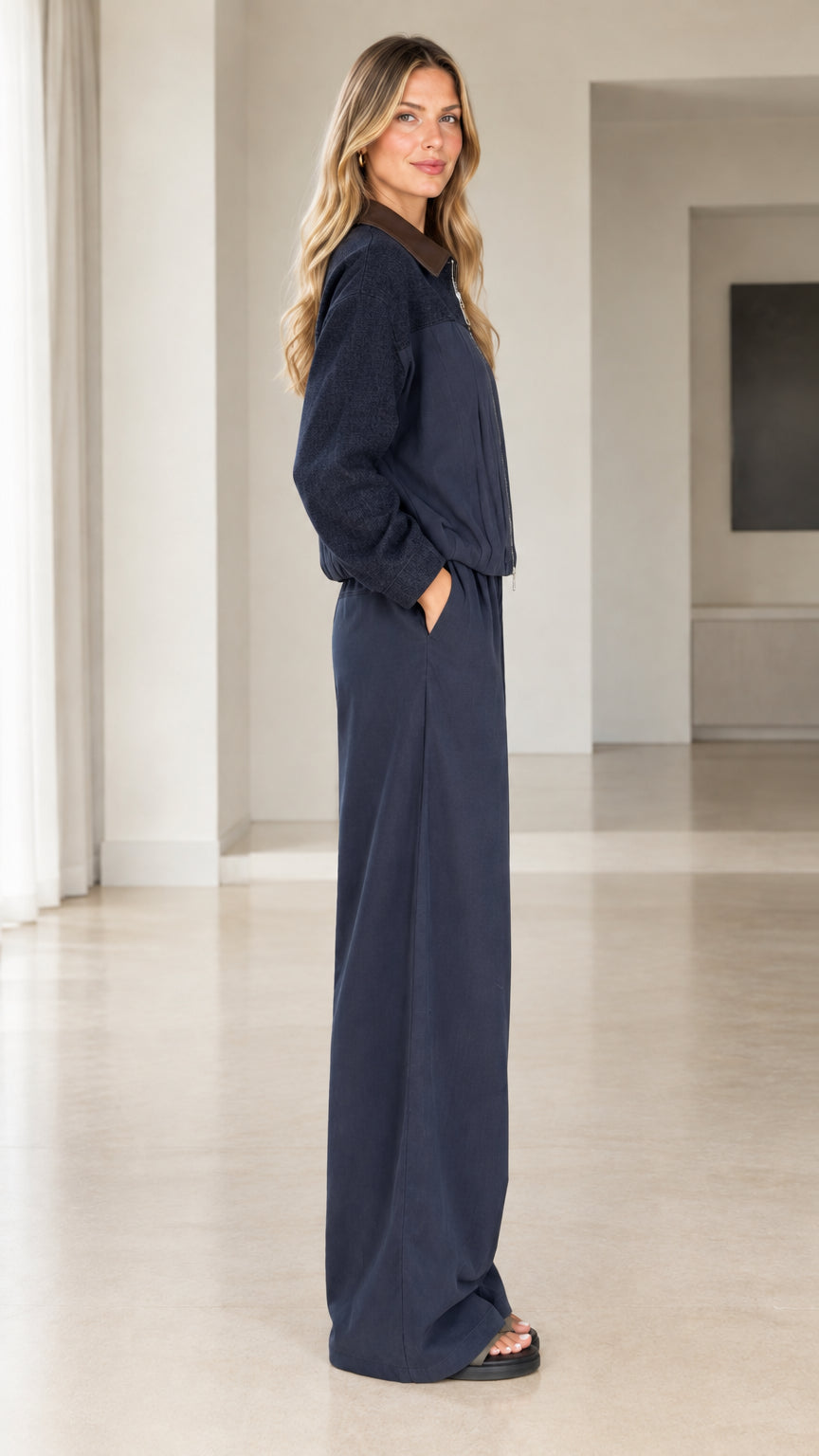 Side profile of woman in navy zip-front jacket and matching wide trousers