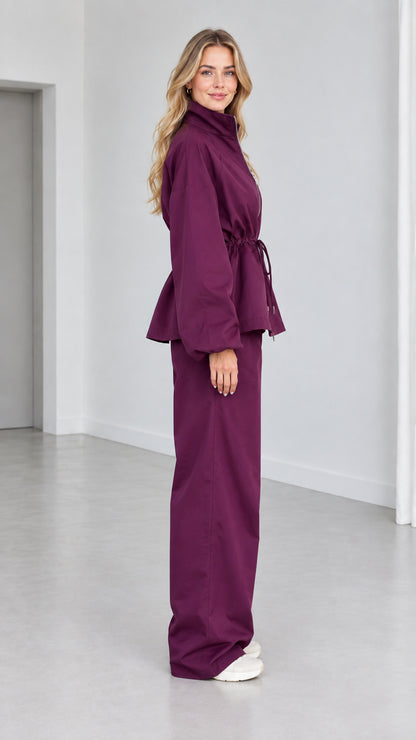 Side view of woman wearing plum matching zip jacket and wide-leg pants set