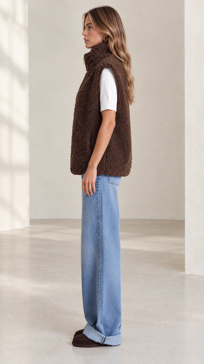 Side profile view of woman wearing brown teddy fleece vest