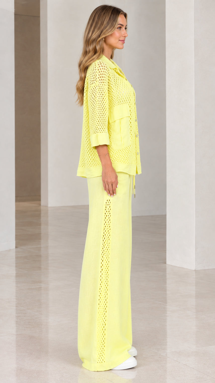 Side profile view of woman wearing light yellow open knit pants set