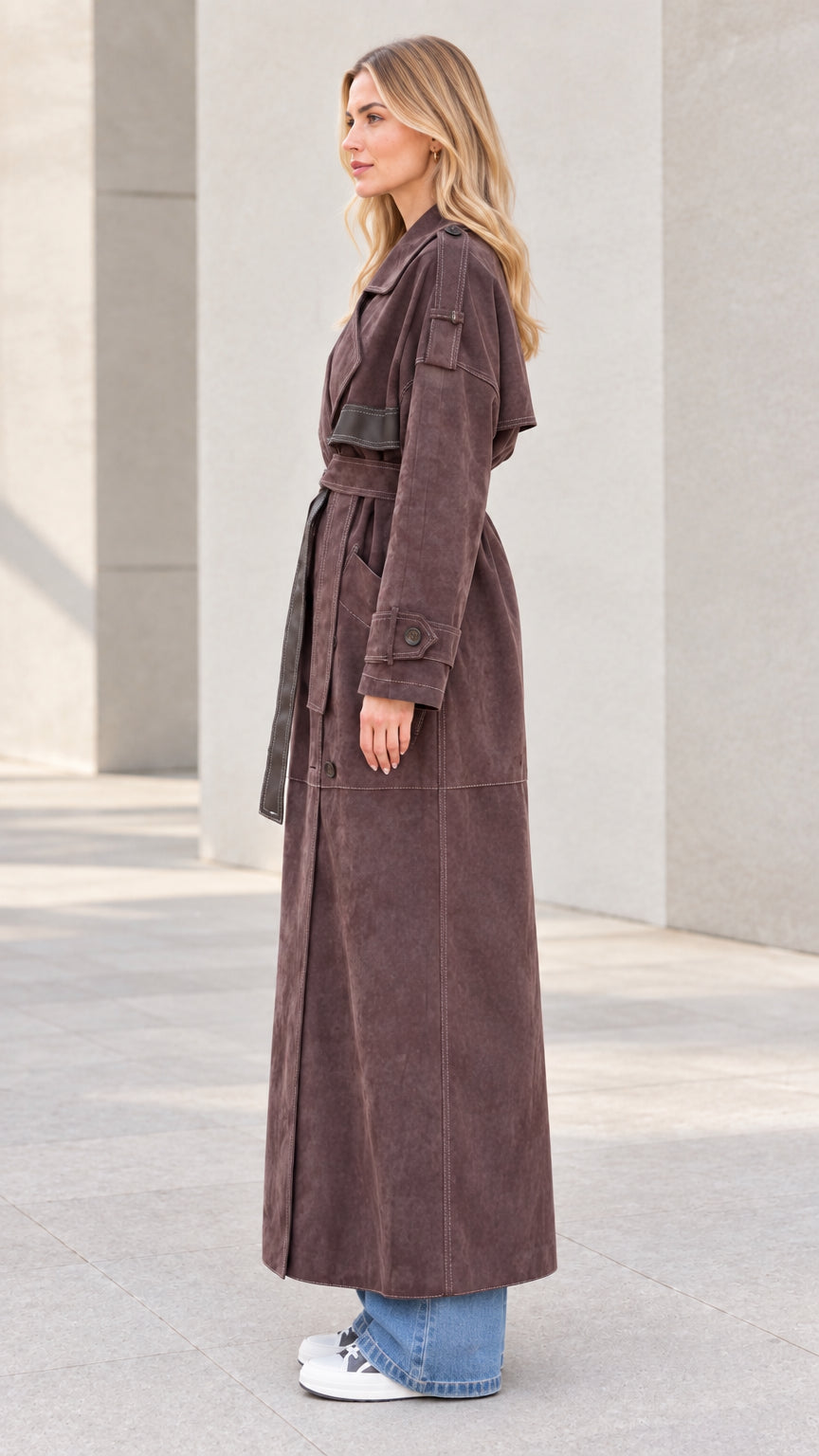 Side profile view of model wearing brown full-length suede duster coat