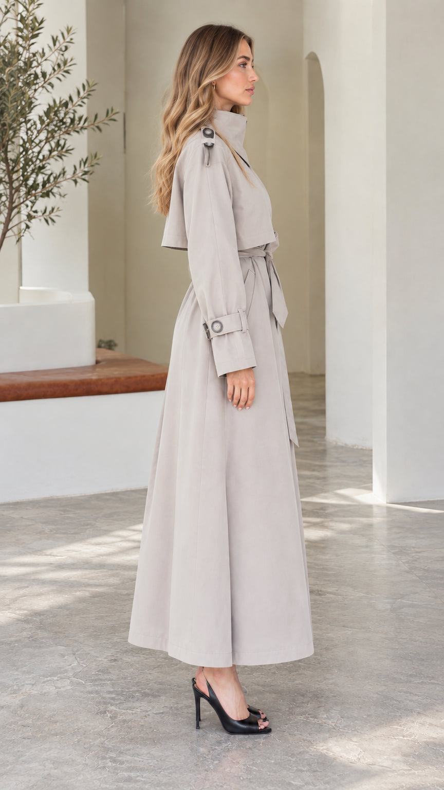 Side profile of model in Light Grey maxi trench coat showing flared hem and sleeve details
