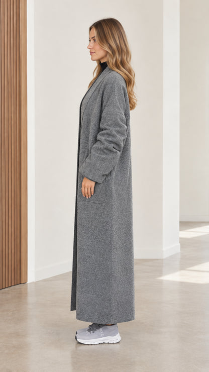 Side profile view of women's full-length grey textured coat