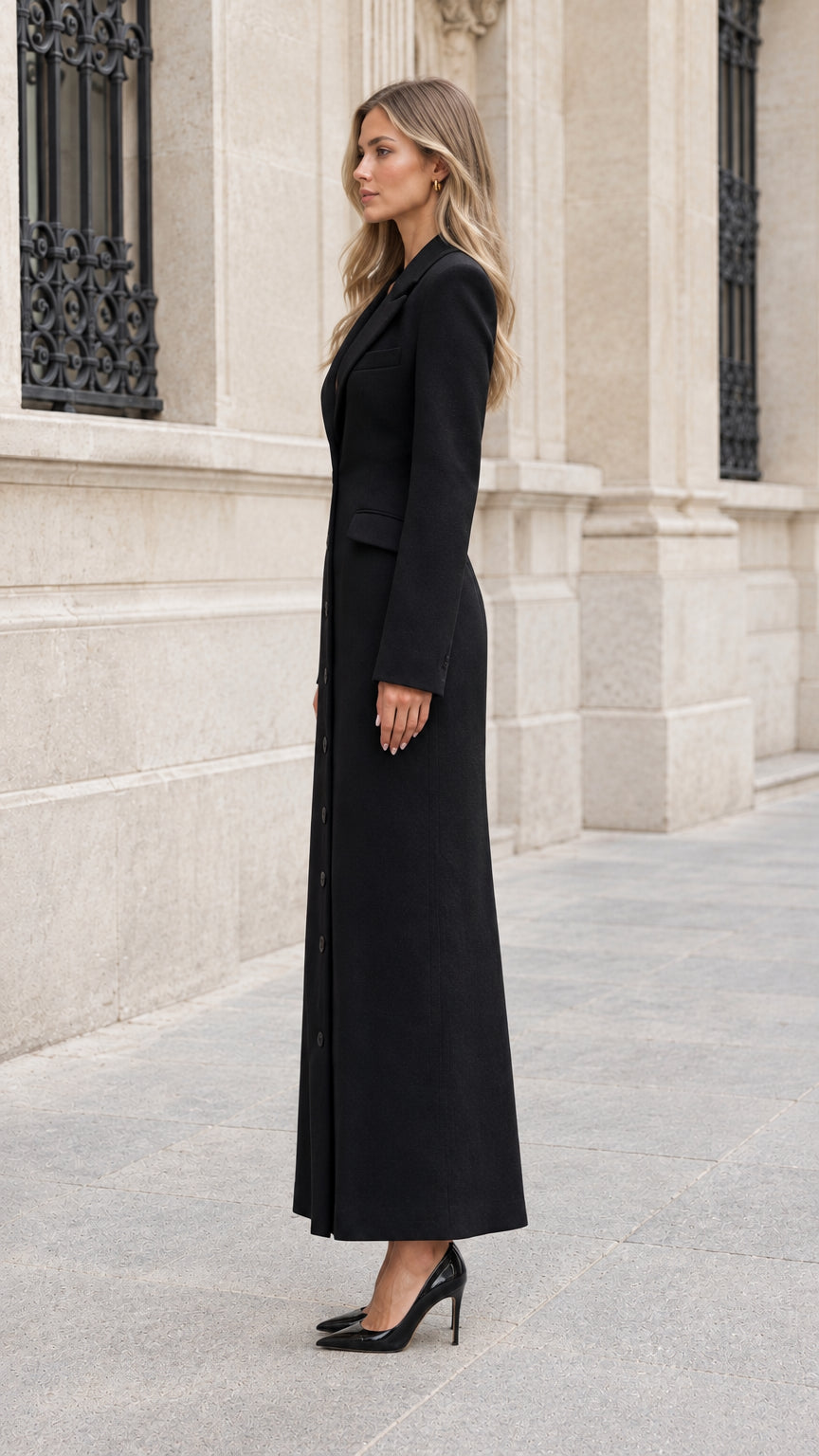 Side view of woman wearing long black single-breasted coat dress