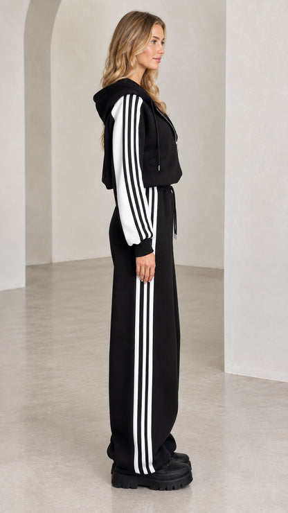 Side profile of model wearing black two-piece striped track set