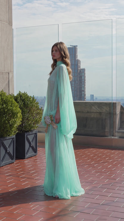 Side profile of model wearing mint green cape sleeve maxi formal dress