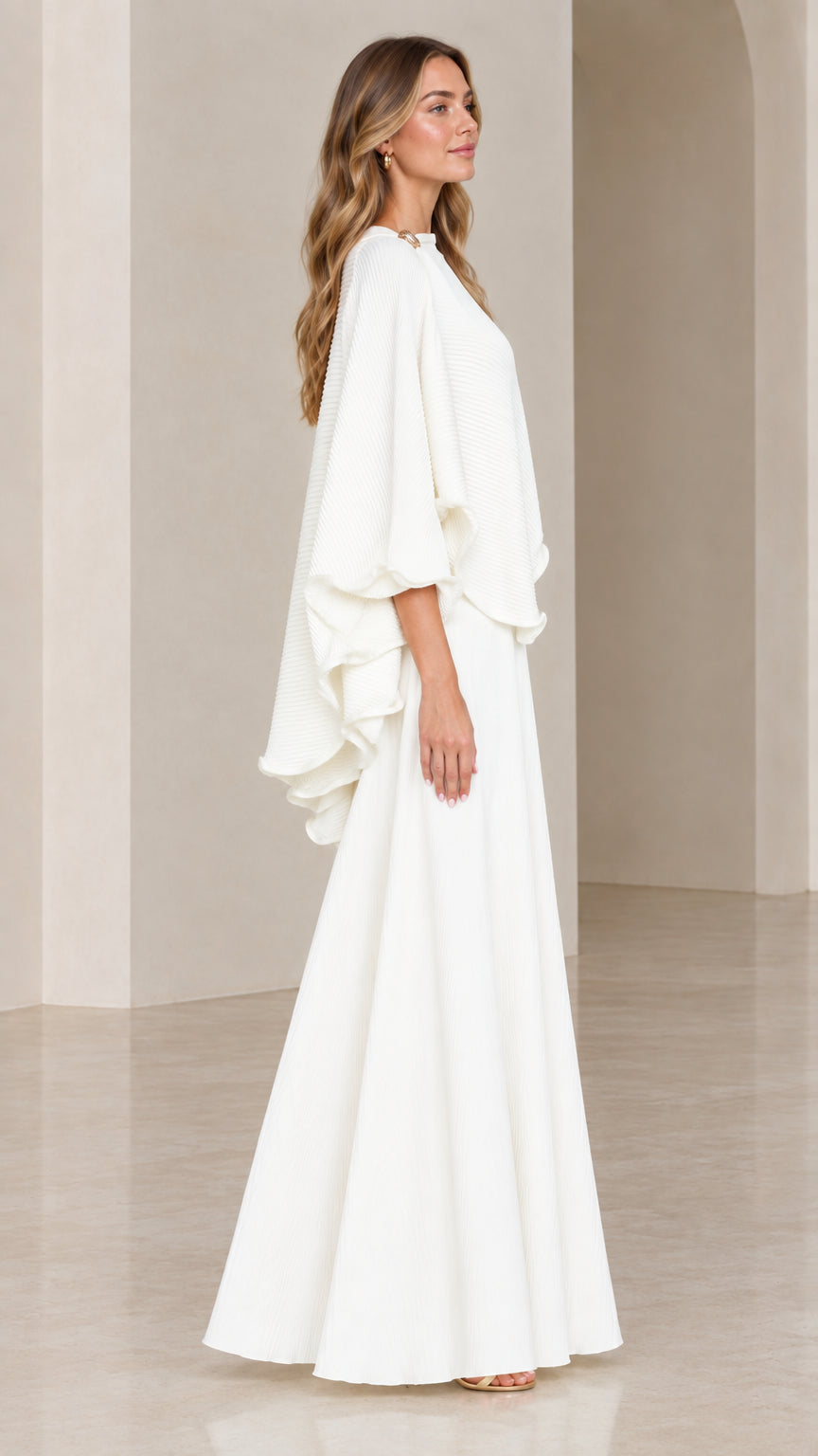Side view of model wearing white flowing capelet and maxi skirt ensemble