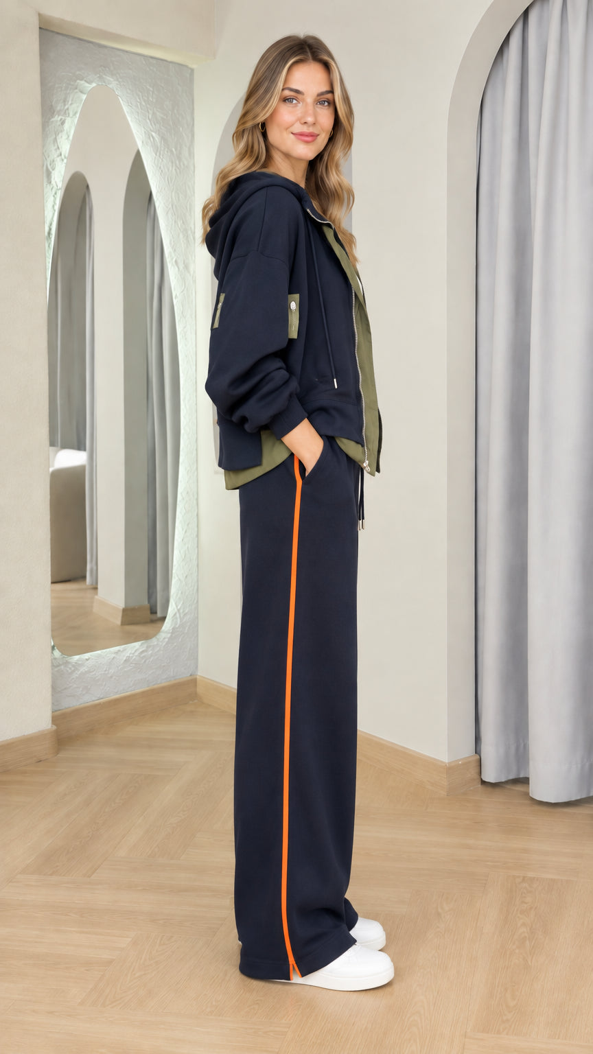 Side profile of woman wearing navy two-piece loungewear set with side stripes