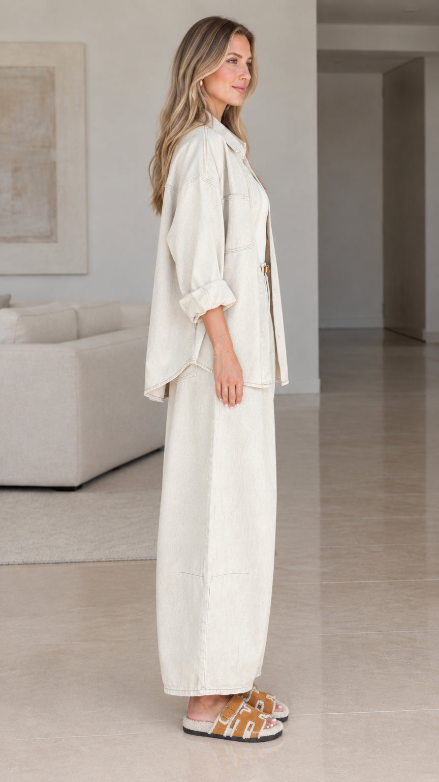 Side angle view of women wearing cream oversized shirt and wide-leg trousers set
