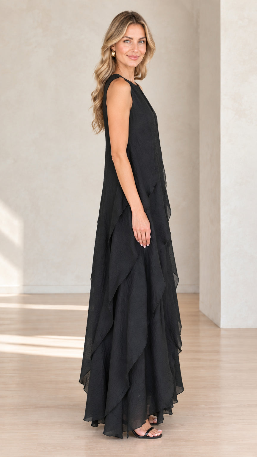 Side profile of model wearing black flowy tiered maxi dress