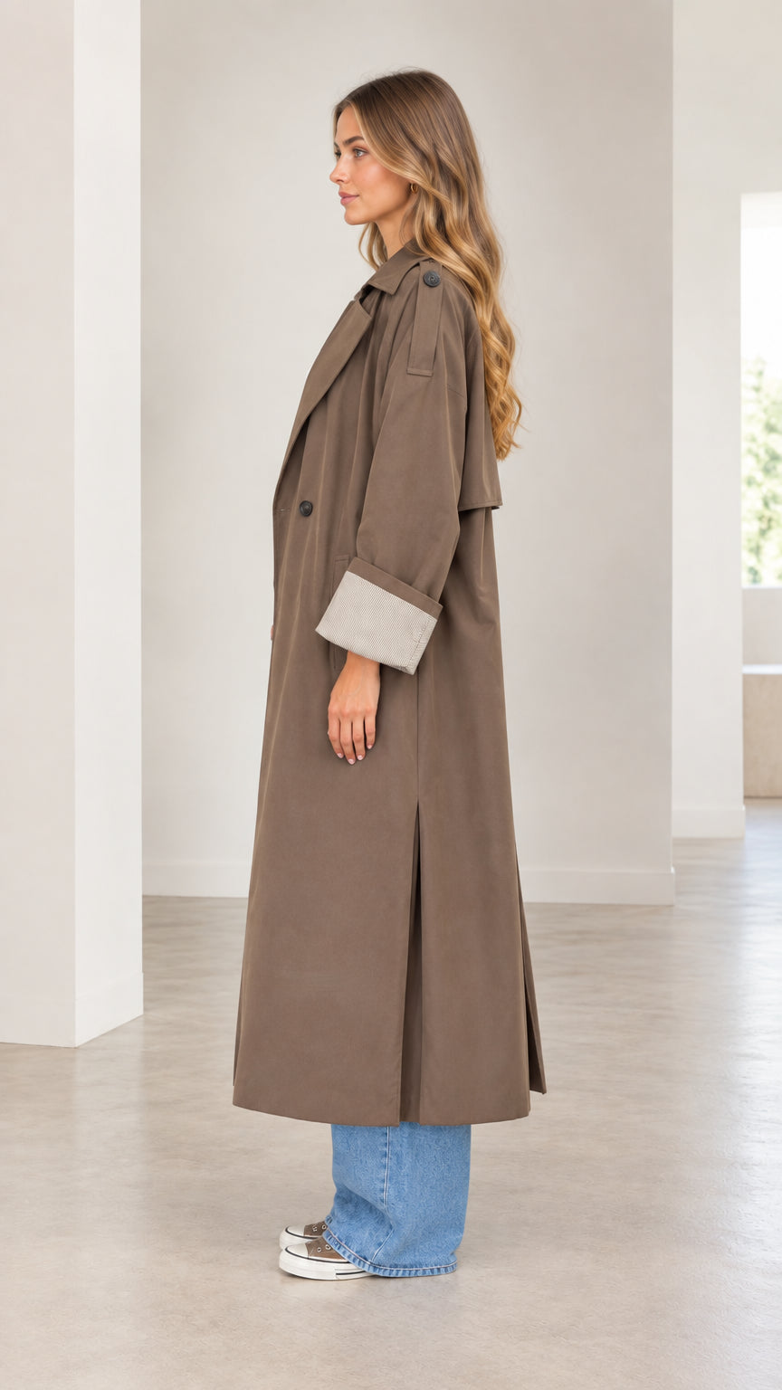 Side profile view of woman modeling the mocha brown longline trench coat with wide-leg jeans