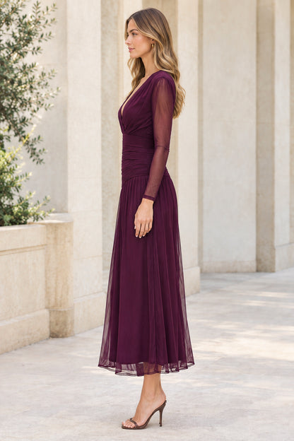 Side angle of woman in plum ruched long sleeve midi evening dress