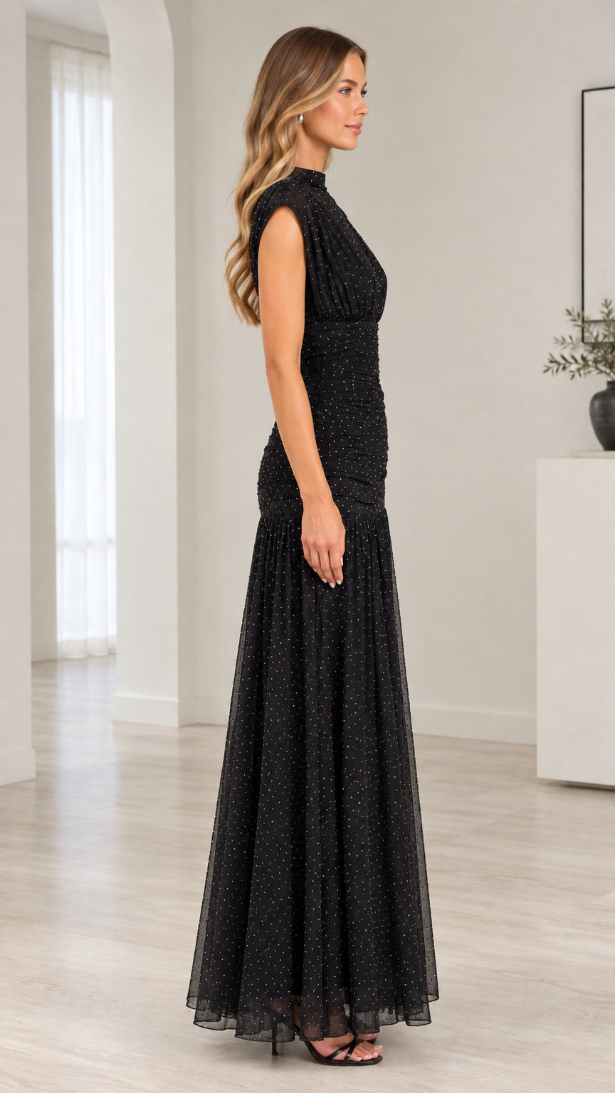 Side profile view of model wearing black glitter mesh high neck evening gown
