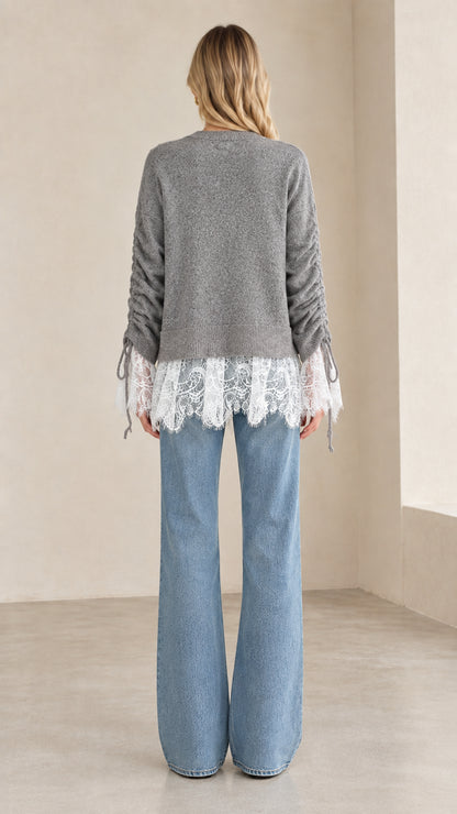 Back view of woman wearing heather grey lace trim knit cardigan with wide-leg denim