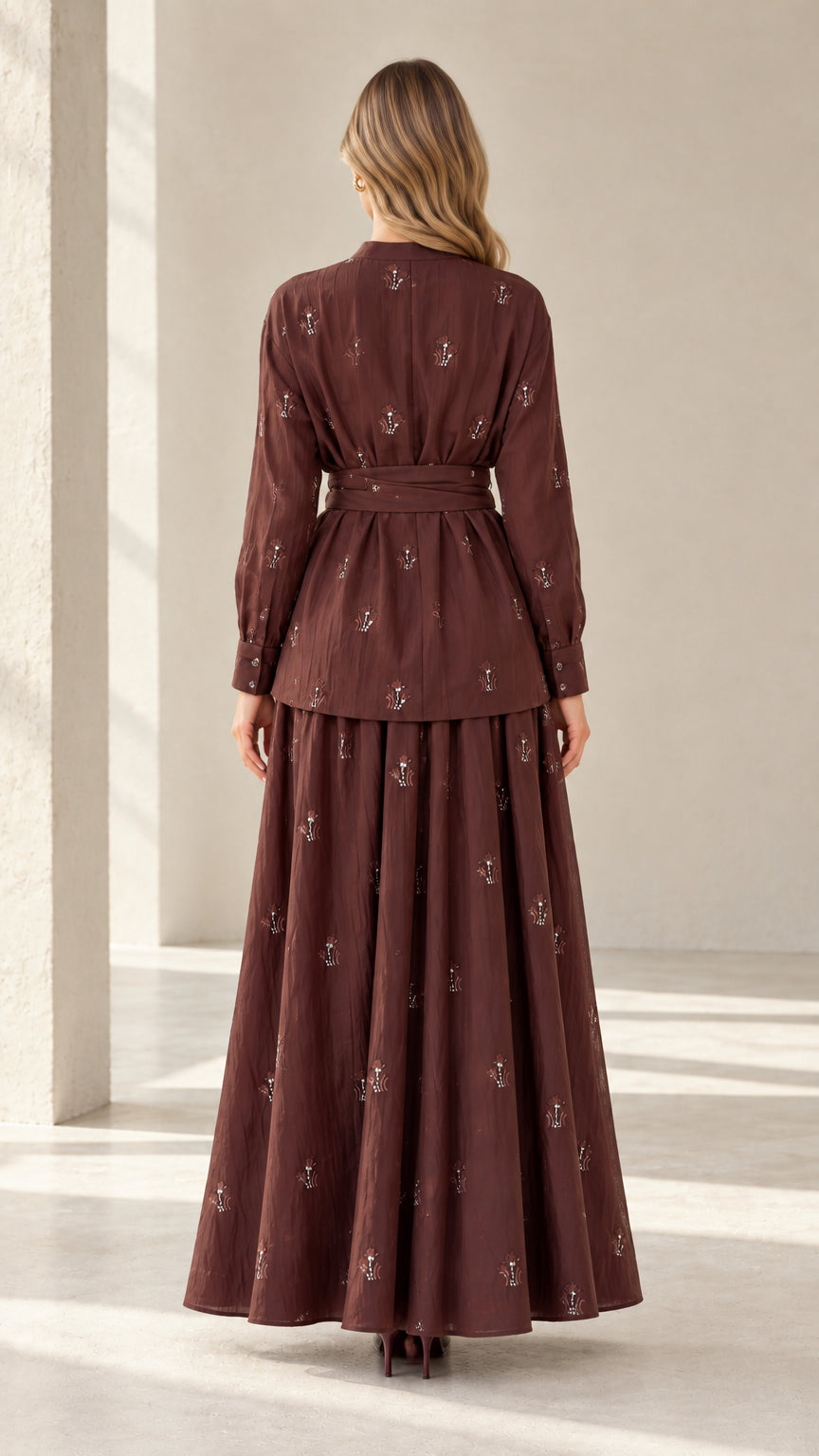 Back view of model in brown belted tunic top and long pleated maxi skirt