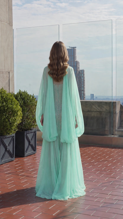 Back view of model wearing flowing mint green cape overlay evening gown