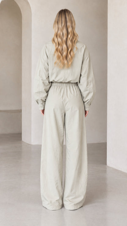 Back view of woman wearing Light Sage wide-leg one-piece jumpsuit with drawstring waist