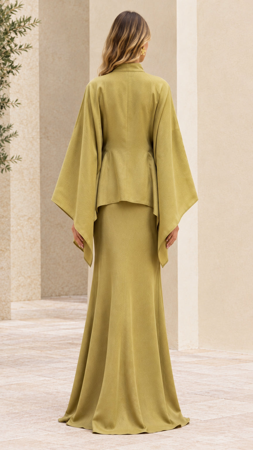 Back view of woman in olive green floor-length cape dress