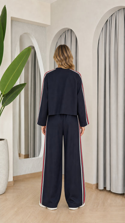 Back view of model wearing navy blue track jacket and wide leg pants