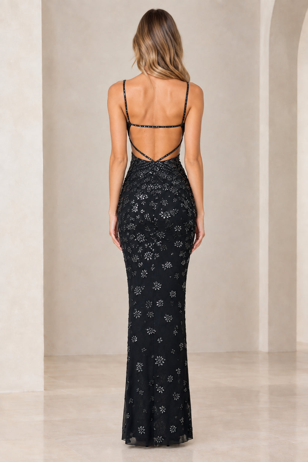Back view of model showcasing low back strap detail of black gown