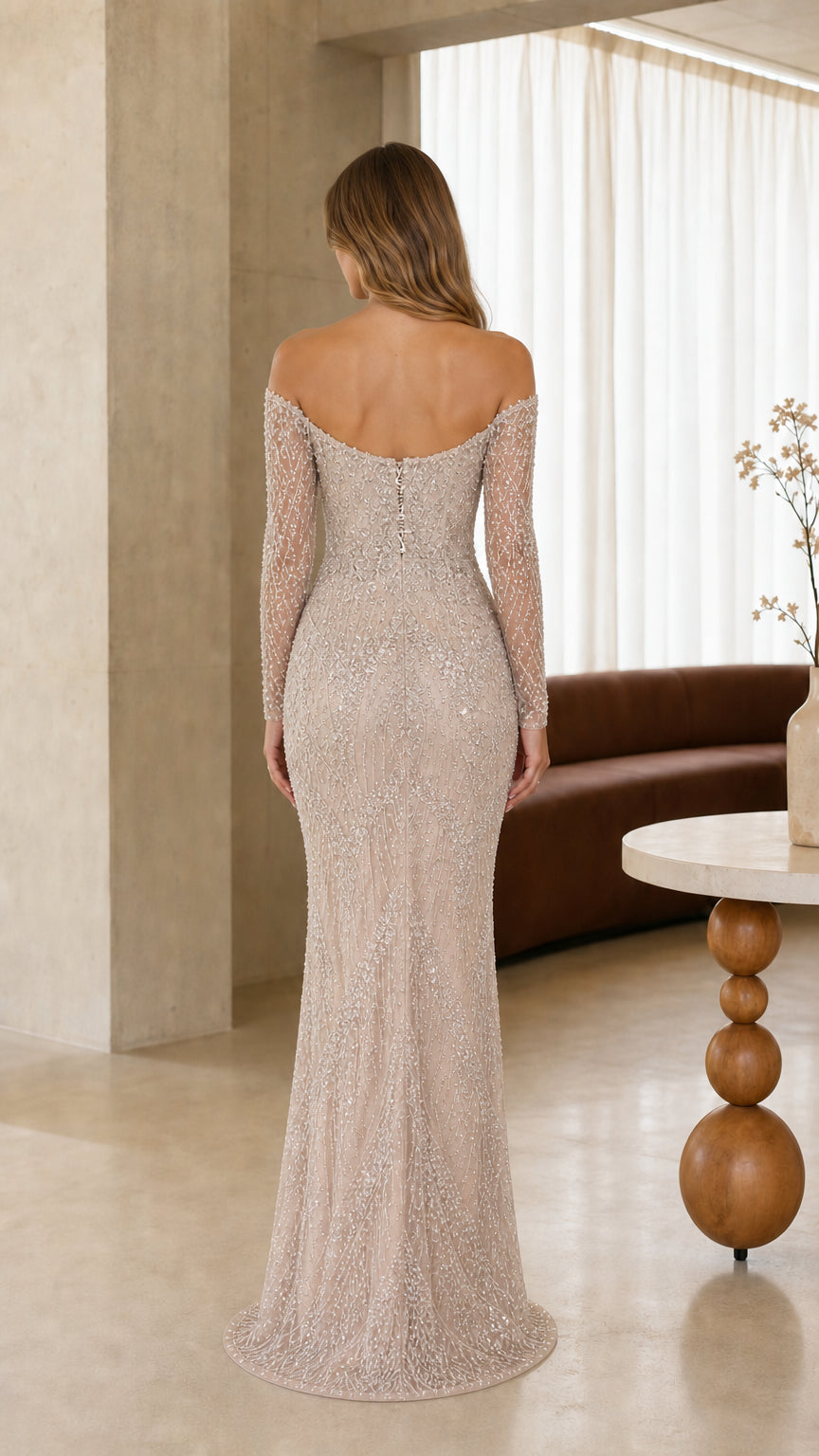 Back view of model showcasing back neckline and floor-length silhouette of champagne evening gown