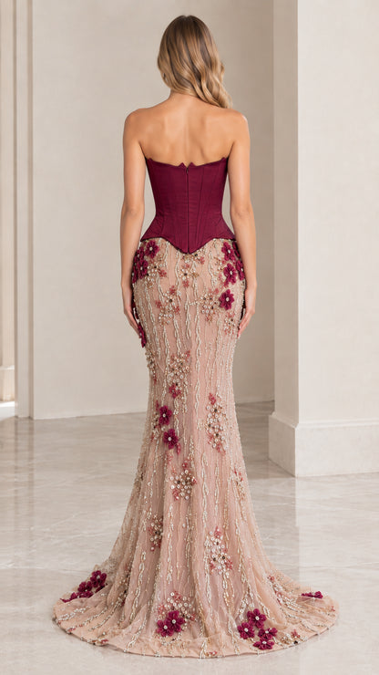 Back view of woman wearing burgundy corset formal gown showing structured boning and mermaid train