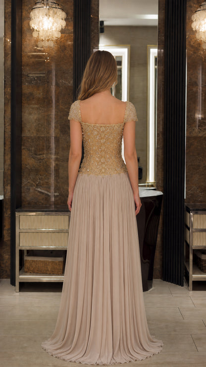 Back view of model wearing the Champagne beaded illusion back pleated formal dress