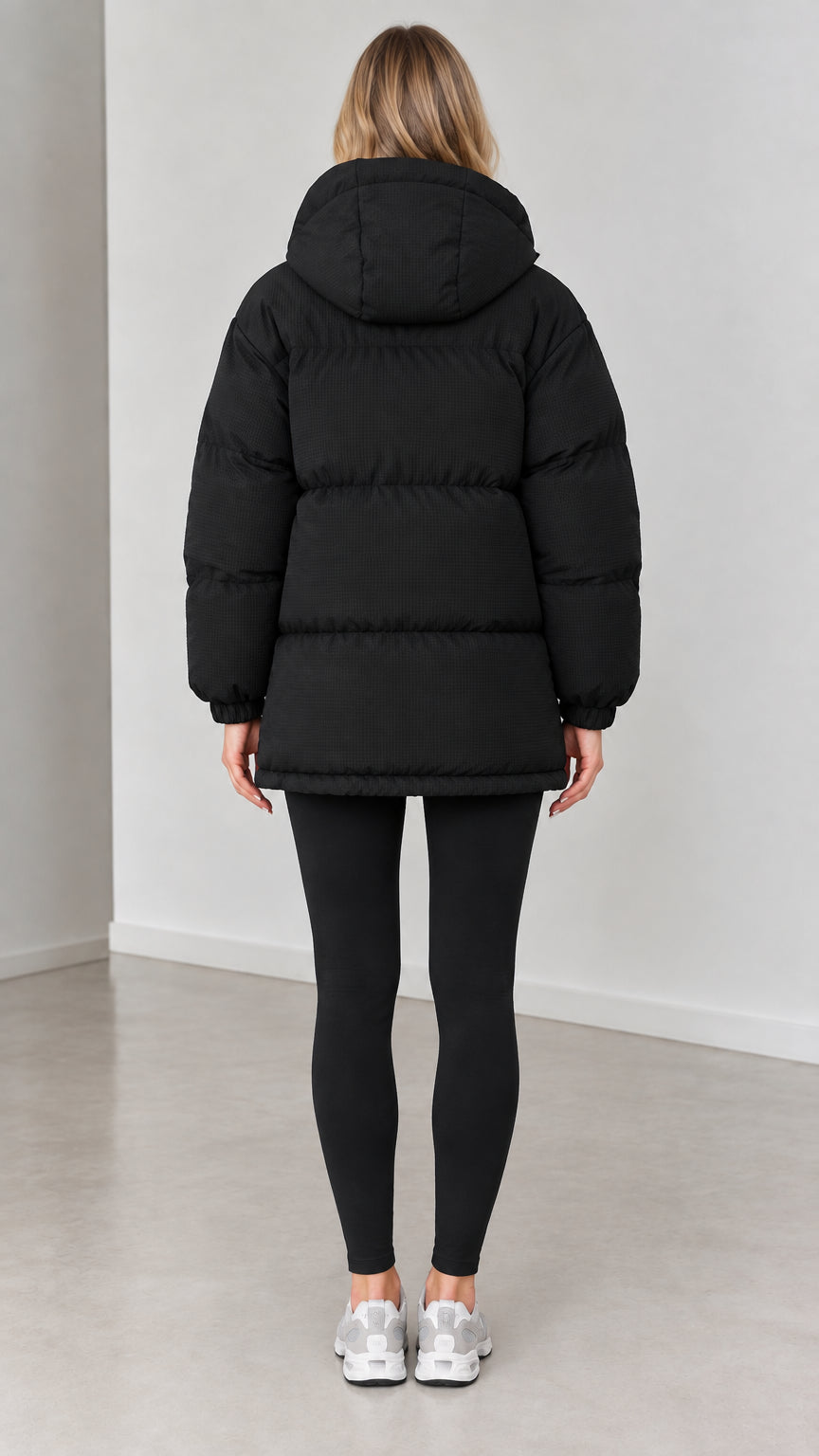 Back view of woman wearing black hooded baffle-quilted winter jacket