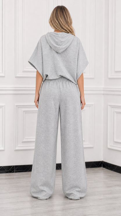 Back view of model wearing heather grey short sleeve hooded top and relaxed wide leg pants