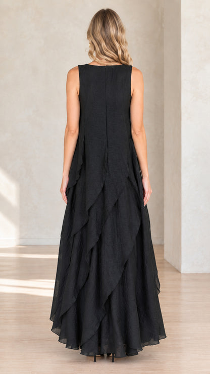 Back view of model wearing black sleeveless maxi dress with tiered layers