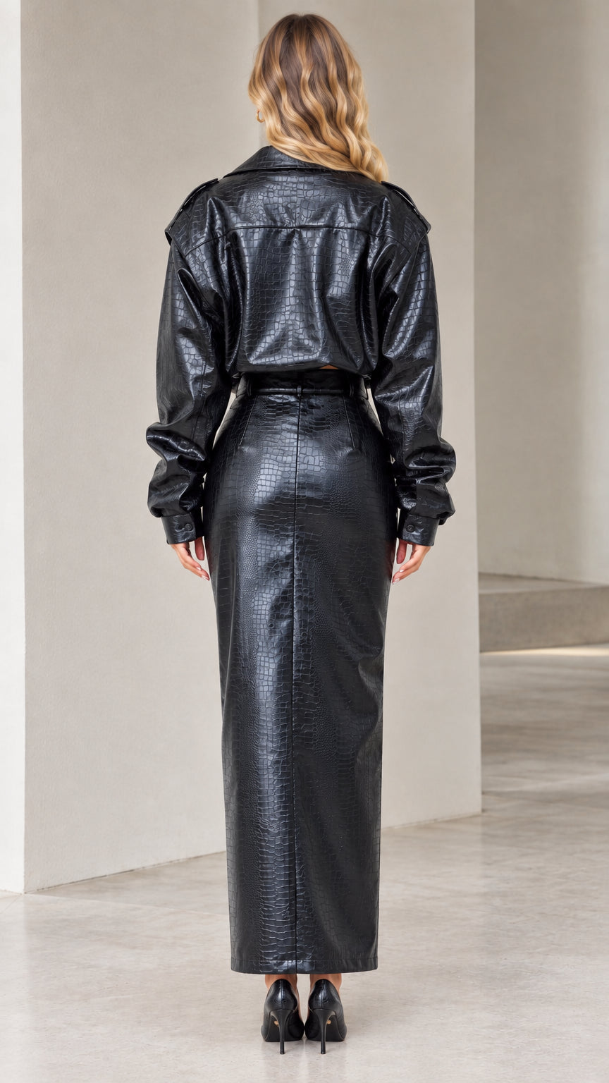 Back view of model wearing black crocodile embossed faux leather cropped jacket and skirt