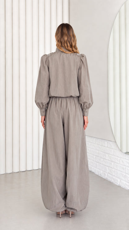 Back view of model wearing taupe grey relaxed-fit long sleeve jumpsuit