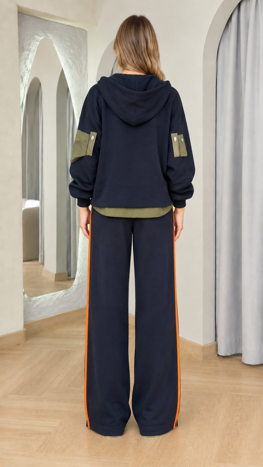 Back view of woman wearing navy hooded tracksuit with wide-leg pants