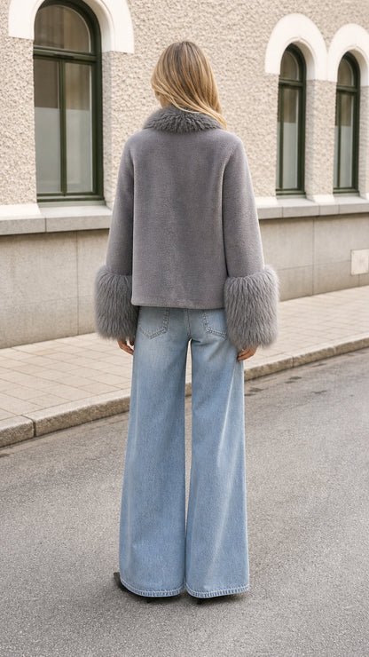 Back view of woman wearing grey faux fur trimmed coat and flared jeans