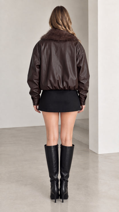 Back view of dark brown faux leather bomber jacket showing elastic hemline