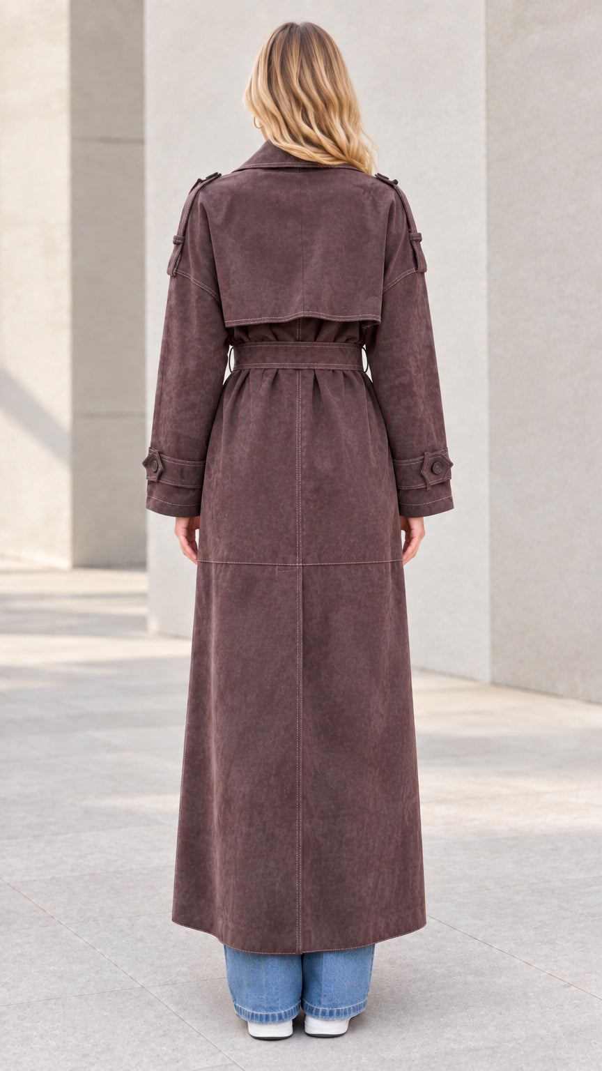 Back view of model wearing brown maxi trench coat with back flap detail