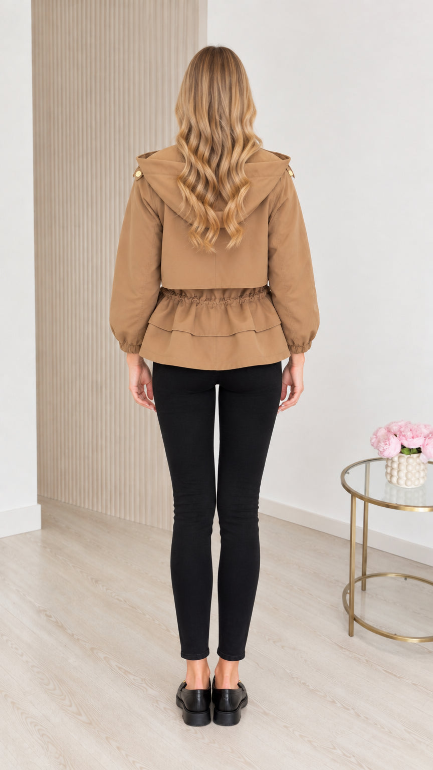 Back view of model wearing camel hooded utility jacket showing cinched waist detail