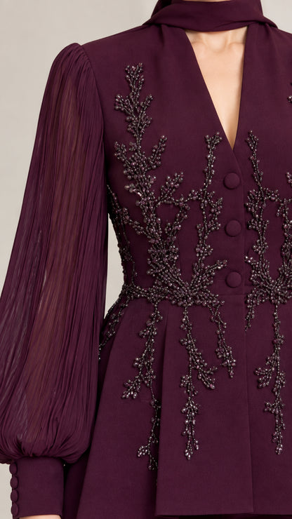 Close-up detail of burgundy beaded embroidery, covered buttons, and sheer sleeves